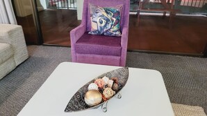 A modern living room with a white coffee table, a purple armchair, and a colorful pillow. - Effortless Homes (East London)