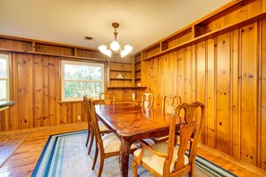 A wooden-paneled dining room with a large table and chairs, a chandelier, and built-in shelves. - Roomy 4BR home in West Knox w/ Patio - 6mi from UT (Knoxville)