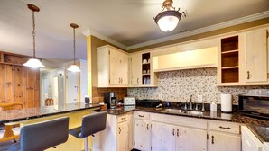 Une cuisine dotée d’un plan de travail en marbre, de meubles blancs et d’un revêtement mural en carreaux.