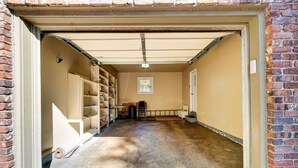 Un garage avec un sol en béton, une porte sur le côté droit et une fenêtre sur le côté gauche.