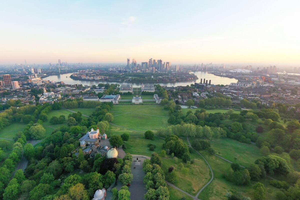 An aerial view of a city with a large park, a river, and a historic building with a dome.