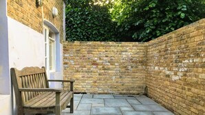 A brick wall with a wooden bench in a courtyard.