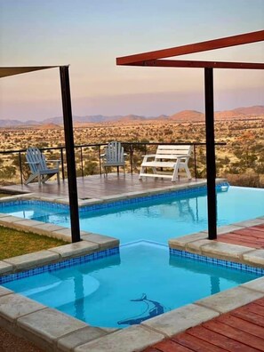 A pool with a clear view of a desert landscape. - Stofpad Namibia (Solitaire)