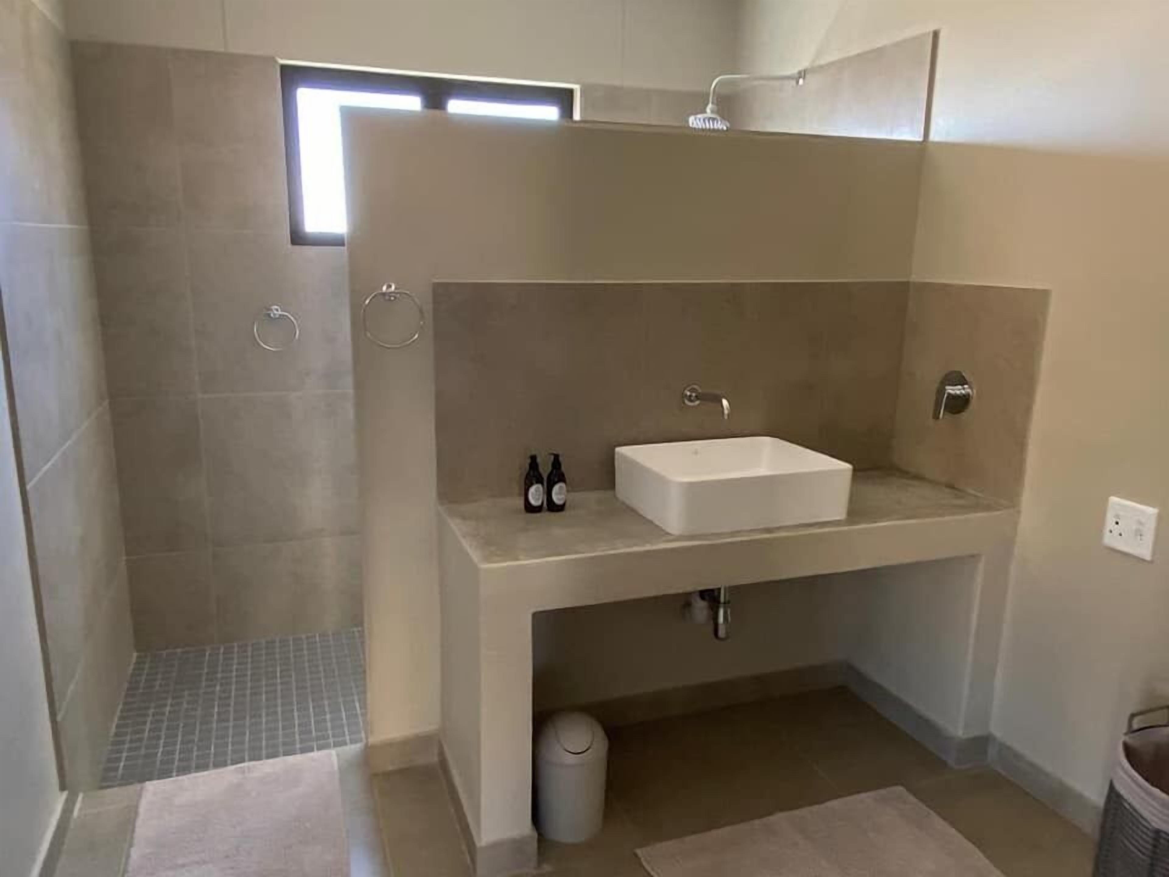Et badeværelse med bruser, håndvask og toilet.