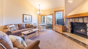 A living room with a fireplace, a sofa, a coffee table, and a TV. - Top Floor w/ Mountain & Ski Slope Views, Ideal Location in River Run Village (Keystone)