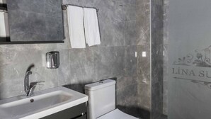 A modern bathroom with a white sink, mirror, and toilet. - Lina Suit Hotel (Istanbul)