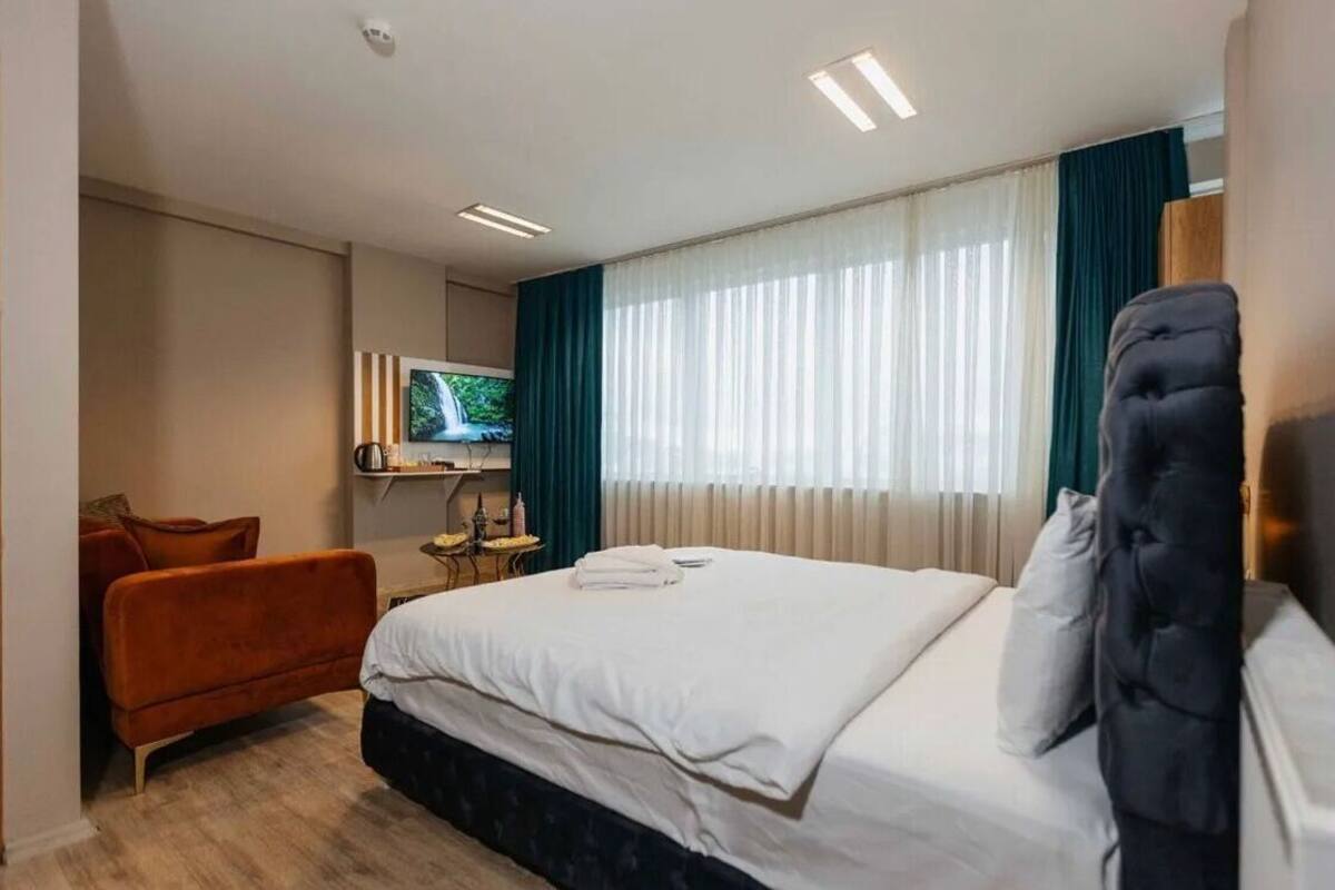 A hotel room with a bed, a TV, a desk, and a chair.