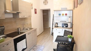 A compact kitchen with a sink, stove, and microwave. There is a small dining area with a table and chairs. - Cinemovie Guesthouse (Rome)