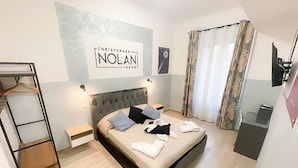 A bedroom with a bed, a wardrobe, a desk, and a framed sign on the wall. - Cinemovie Guesthouse (Rome)