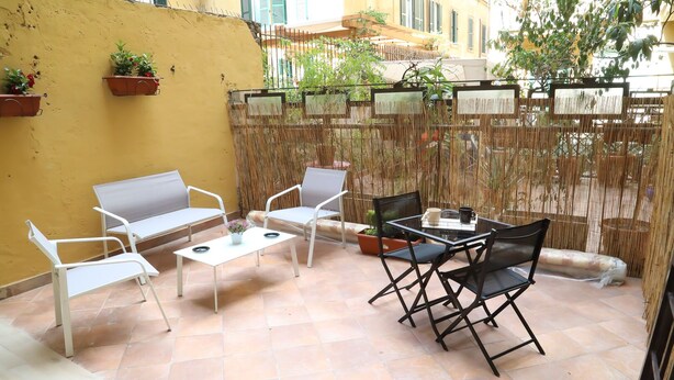 A patio with white and black furniture, including a sofa, chairs, and a table. - Cinemovie Guesthouse (Rome)