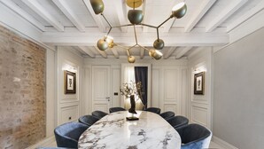 A conference room with a marble table, blue chairs, a chandelier, and framed pictures on the walls.