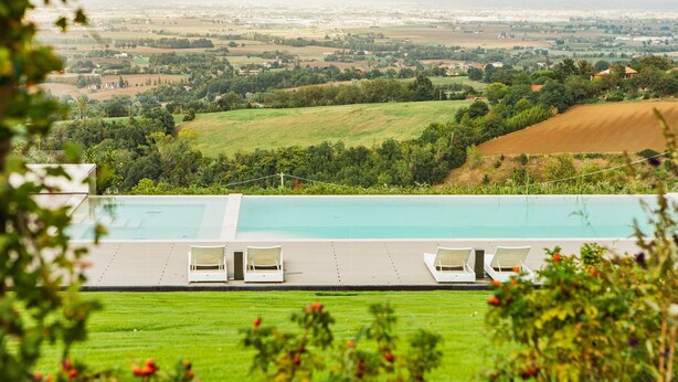 A pool with lounge chairs and a view of a rural landscape.