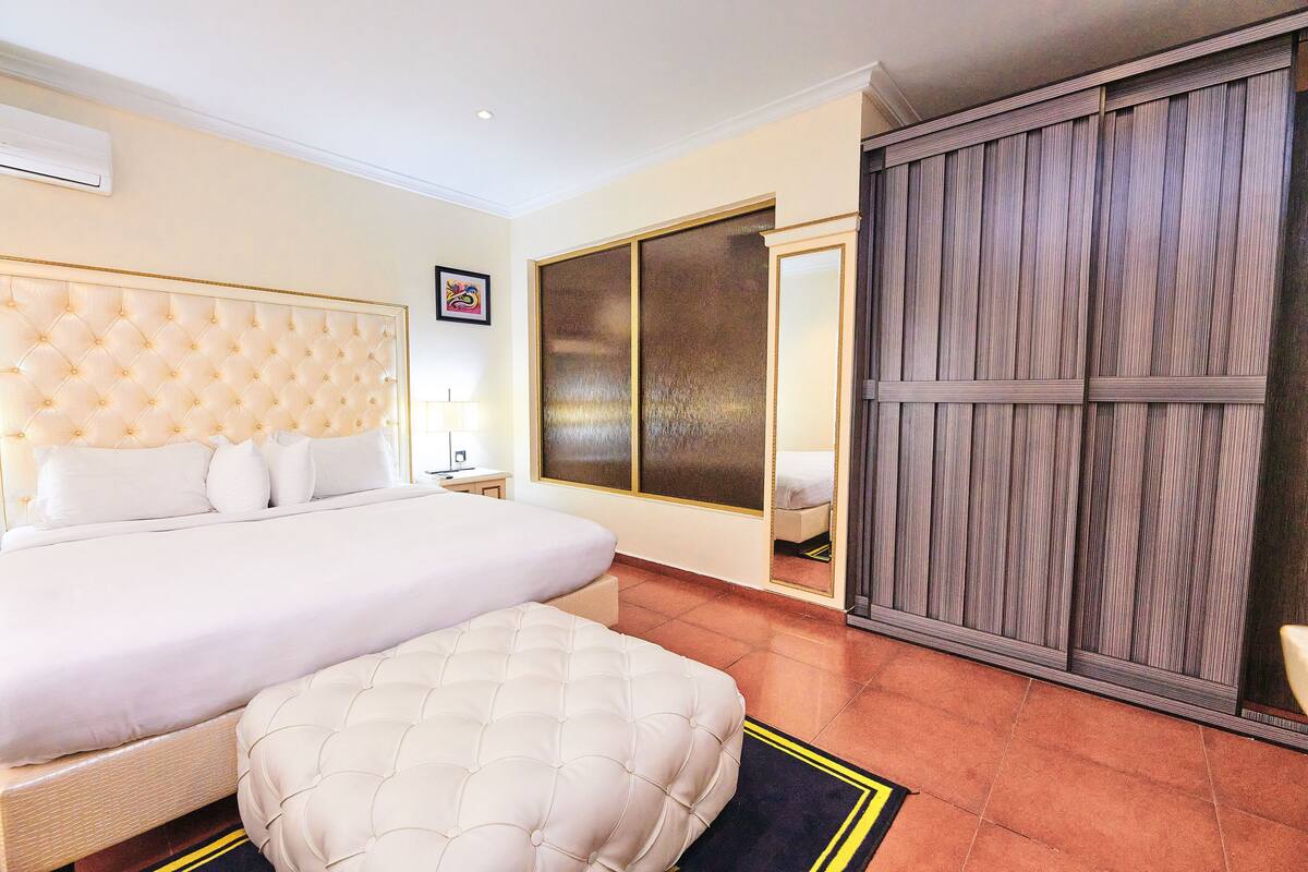 A hotel room with a large bed, a bedside table, a wardrobe, and a mirror.