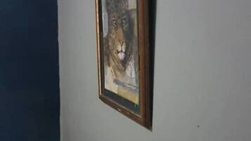 Un cuadro con un león en una pared de una habitación, con una pared lisa y una esquina oscura.