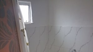 Un bany petit amb vàter, suport de paper higiènic i finestra.