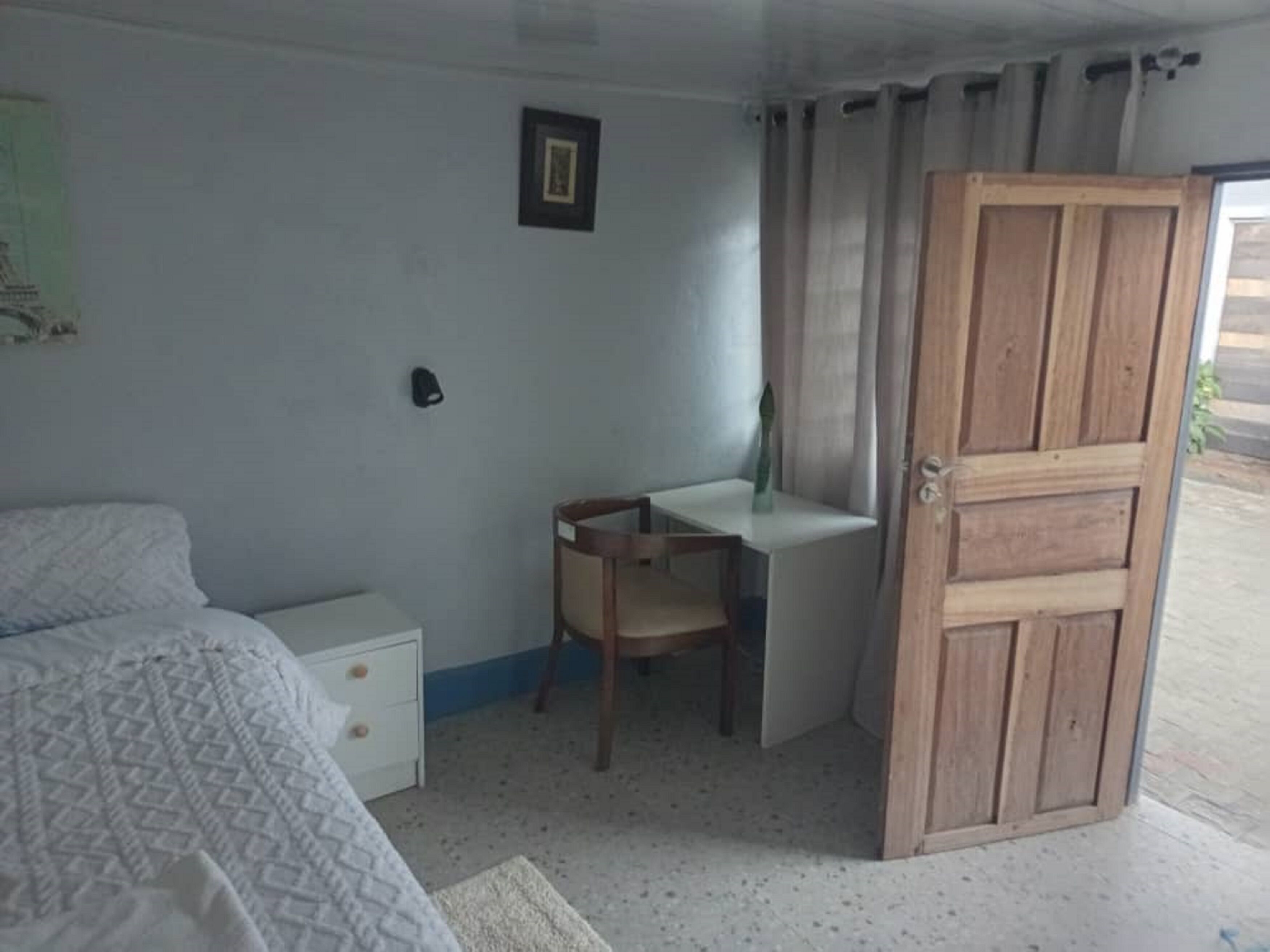 Una camera da letto con un letto, una scrivania, una sedia e una porta in legno.