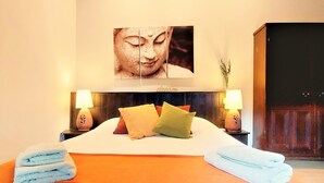 Une chambre d’hôtel comprenant un lit, des oreillers, une table de chevet, une lampe et une œuvre d’art murale.