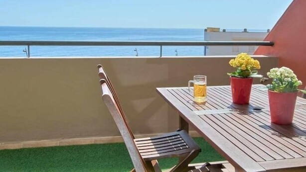A wooden table with a beer mug and potted plants on a balcony overlooking the sea. - Beautiful holiday home with sea views +beach+WIFI (El Rosario)