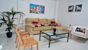 A modern living room with a beige sofa, patterned cushions, a glass coffee table, wicker chairs, and a potted plant. - Beautiful holiday home with sea views +beach+WIFI (El Rosario)