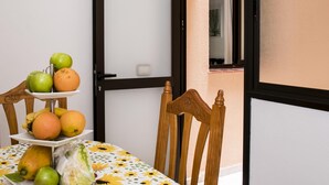 A dining area with a table set for two, a chair, and a window with a view of the outside. - Confortable vivienda en La Laguna a 5 Min tranvía (San Cristobal De La Laguna)