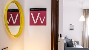 A hotel room with a bed, a bedside table, a lamp, a mirror, and two signs on the wall. - Confortable vivienda en La Laguna a 5 Min tranvía (San Cristobal De La Laguna)