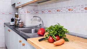 A kitchen with a sink, a cutting board with vegetables, and a cabinet with a spice rack. - Confortable vivienda en La Laguna a 5 Min tranvía (San Cristobal De La Laguna)