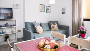 A modern living room with a grey sofa, colorful pillows, a dining table with a red mat, and a small potted plant. - Confortable vivienda en La Laguna a 5 Min tranvía (San Cristobal De La Laguna)