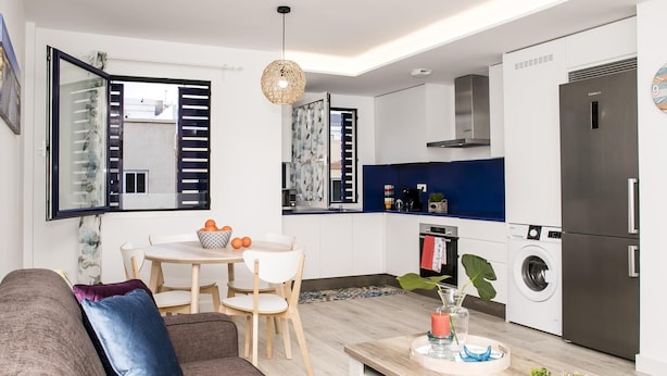 Una cocina moderna con armarios blancos, un refrigerador de acero inoxidable y un horno empotrado.