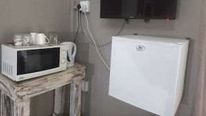 A kitchenette with a microwave, kettle, and a small fridge.
