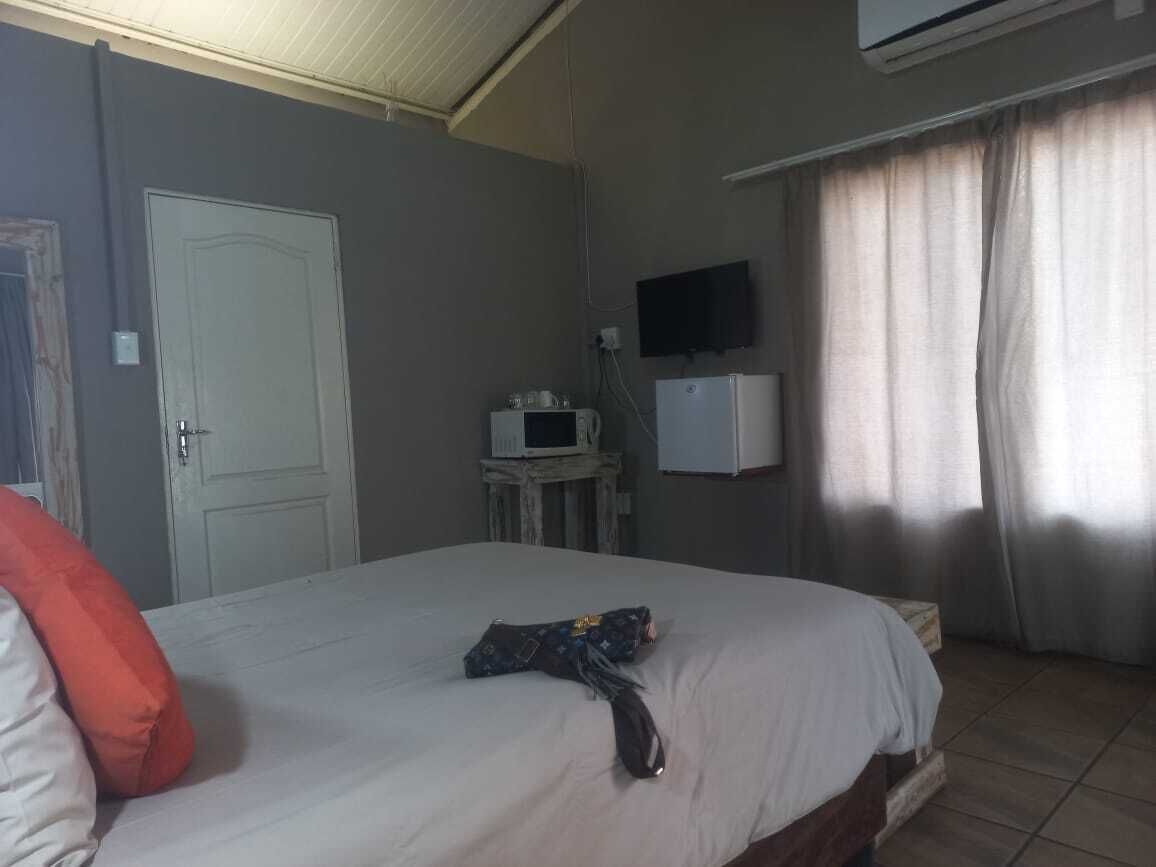 A hotel room with a bed, a television mounted on the wall, a small table with a microwave, and a door.