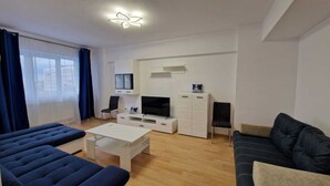 Ein modernes Wohnzimmer mit einer Couch, einem Couchtisch, einem Fernseher und einem TV-Schrank.