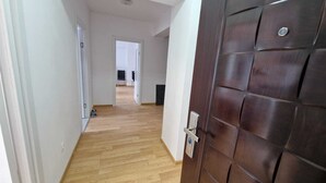 Ein Flur mit Holzboden und einer dunkelbraunen Tür mit silbernem Griff.
