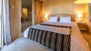 Ein Hotelzimmer mit einem großen Bett, zwei Nachttischlampen, einer Schiebetür und einem Teppichboden.