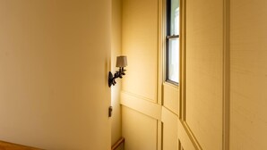 Ein schmaler Korridor mit einer Holzhandläufe, einer Lampe und einem Fenster.