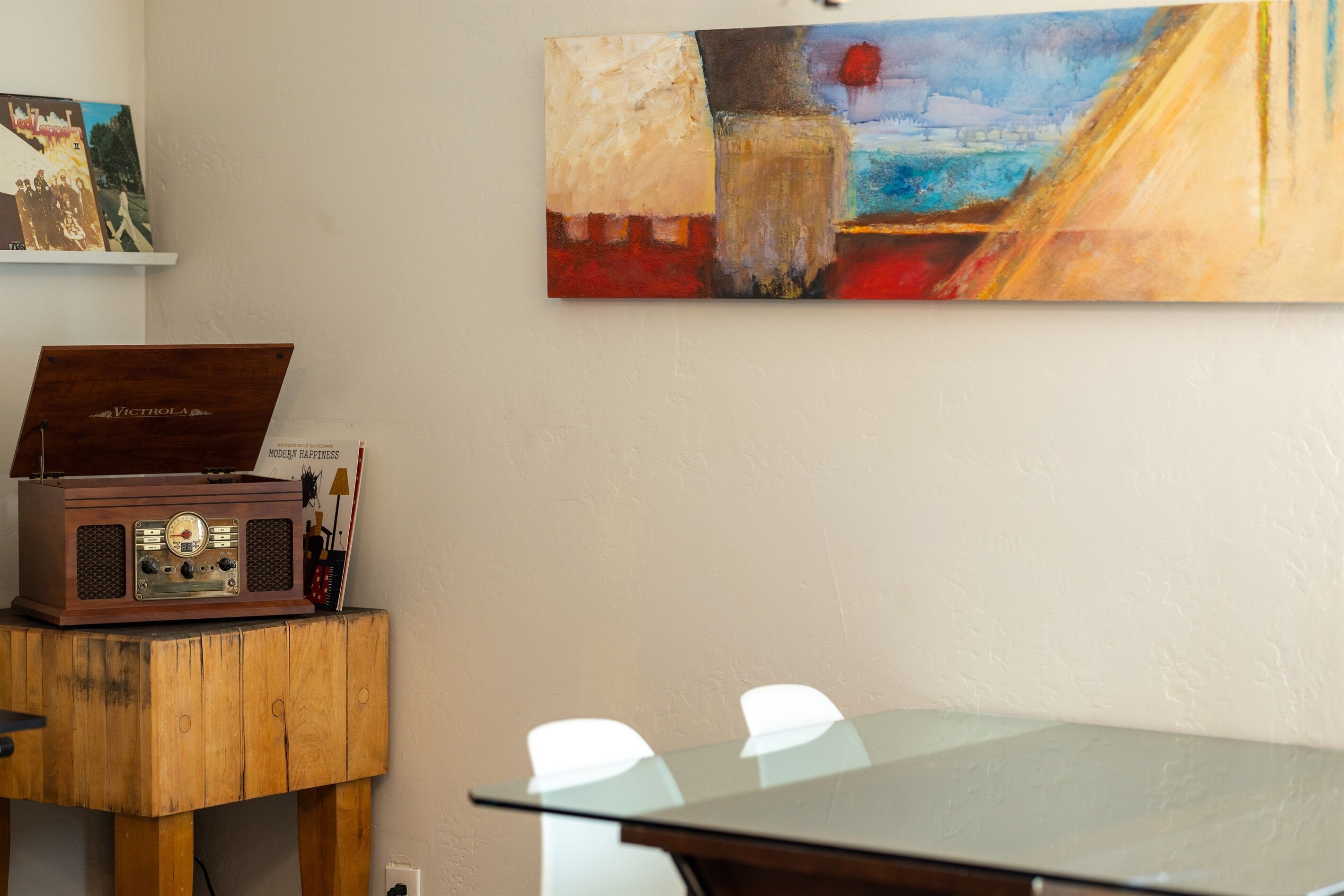 A room with a wooden table, a vintage radio, and a painting on the wall.