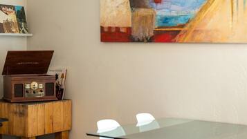 A room with a wooden table, a vintage radio, and a painting on the wall.