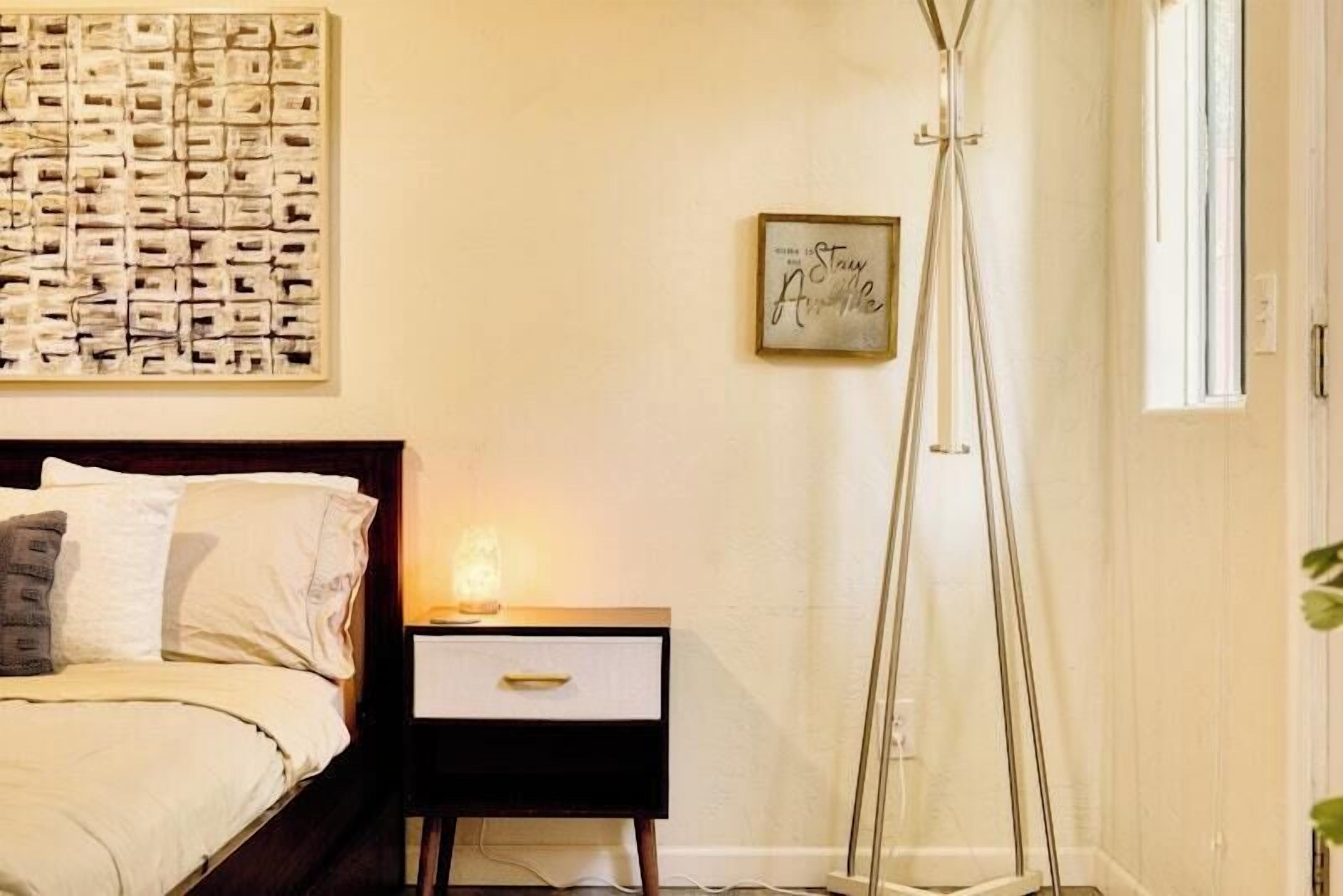 Une chambre à coucher avec un lit, une table de chevet et une lampe sur pied.