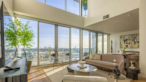 Een ruime woonkamer met een groot raam en uitzicht over de stad, een moderne bank, een bijzettafeltje en een minimalistische inrichting.
