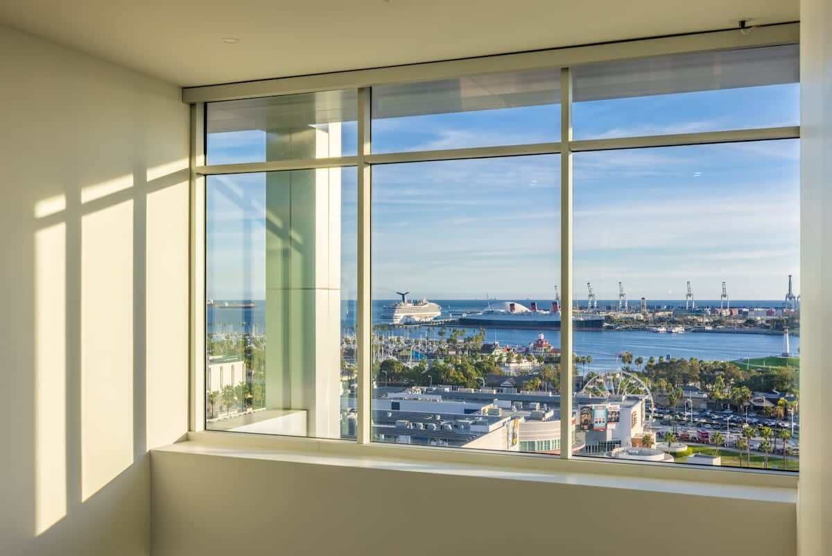 Ein Zimmer mit großem Fenster und Blick auf einen Hafen mit Schiffen und einem Yachthafen.