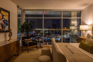 Une chambre d’hôtel moderne dotée d’une grande fenêtre donnant sur la ville, d’un canapé, d’une petite table et d’une plante décorative.