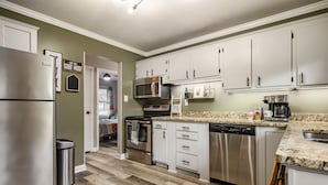 A modern kitchen with stainless steel appliances, white cabinets, and a granite countertop. - The Jungalow: 65" 4K TV, memory foam, kid-friendly (Louisville)