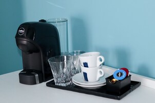 Uma máquina de café, um copo e uma xícara sobre uma bandeja.