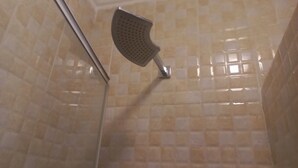 Doccia con soffione a mano in bagno con pareti piastrellate color beige.