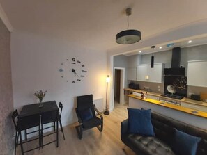 A modern living room with a dining area, a kitchen, and a large wall clock. - Apartment49Oban, very close to Town center. (Oban)