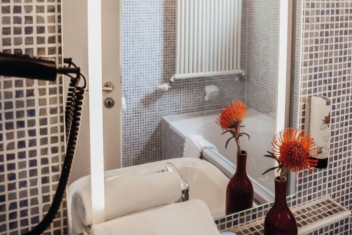 Un bagno con doccia, lavandino e due vasi con fiori.