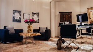 Een moderne woonkamer met een donkere bank, een salontafel en een bureau met een computer.