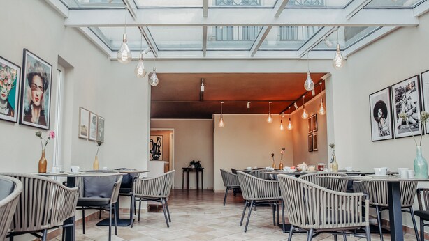 Een moderne eetruimte met hoge plafonds, dakramen en moderne verlichting.