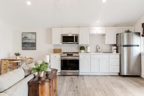Una cocina moderna con armarios blancos, electrodomésticos de acero inoxidable y una zona de comedor de madera.