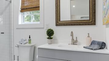 Un baño moderno con inodoro, lavamanos y espejo.