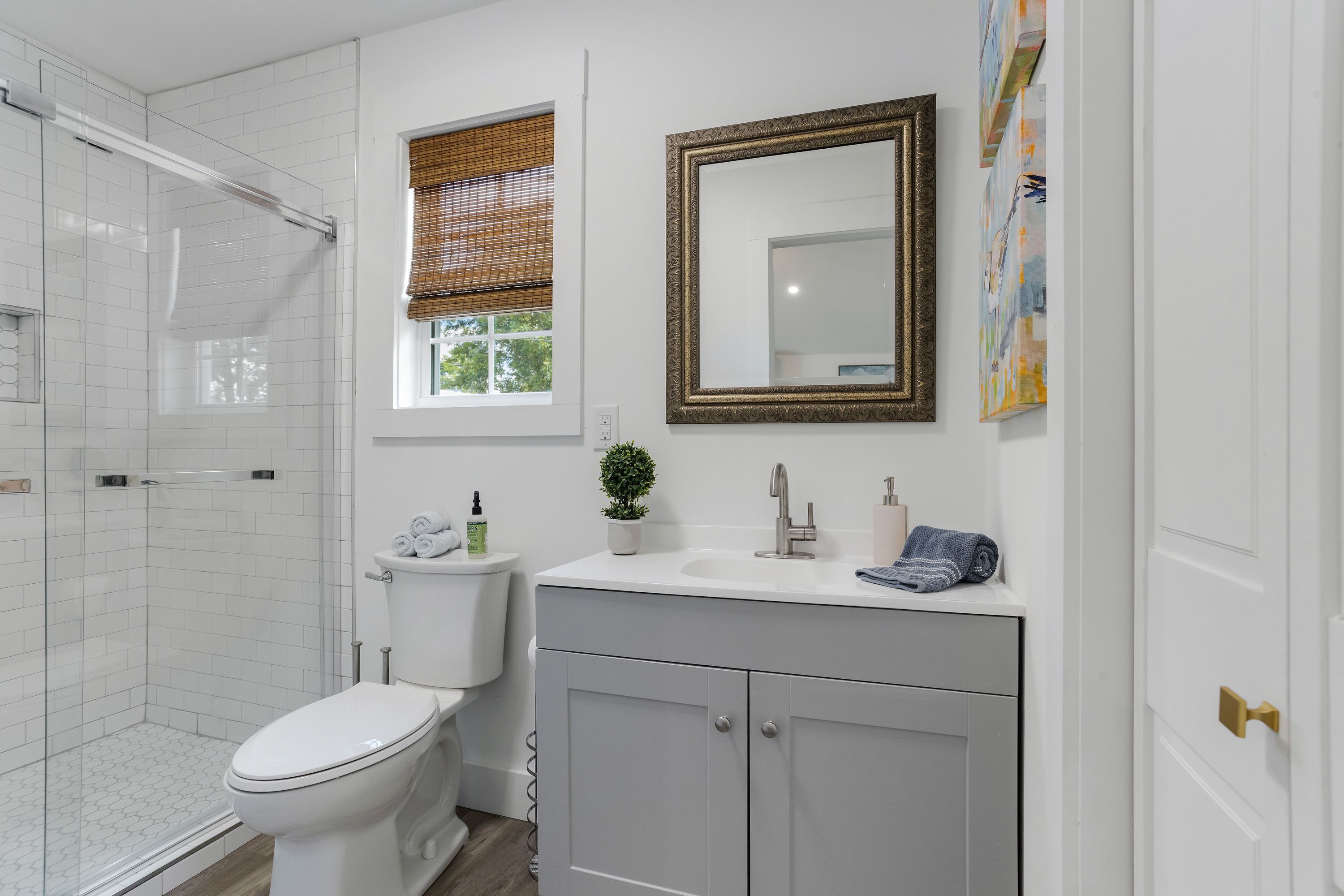 A bathroom with a shower, toilet, sink, and cabinets.